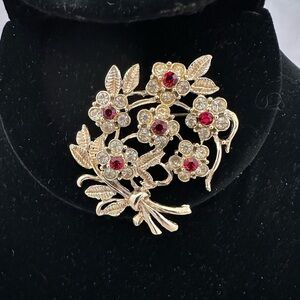Vintage gold tone floral brooch with red and clear rhinestones